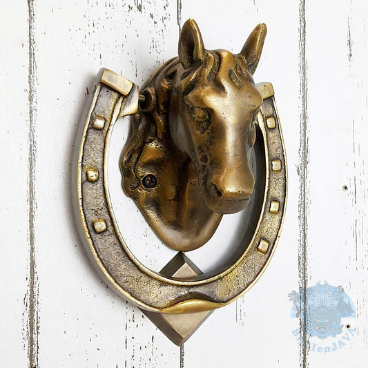 Brass horse head door knocker with horseshoe on a painted wooden background