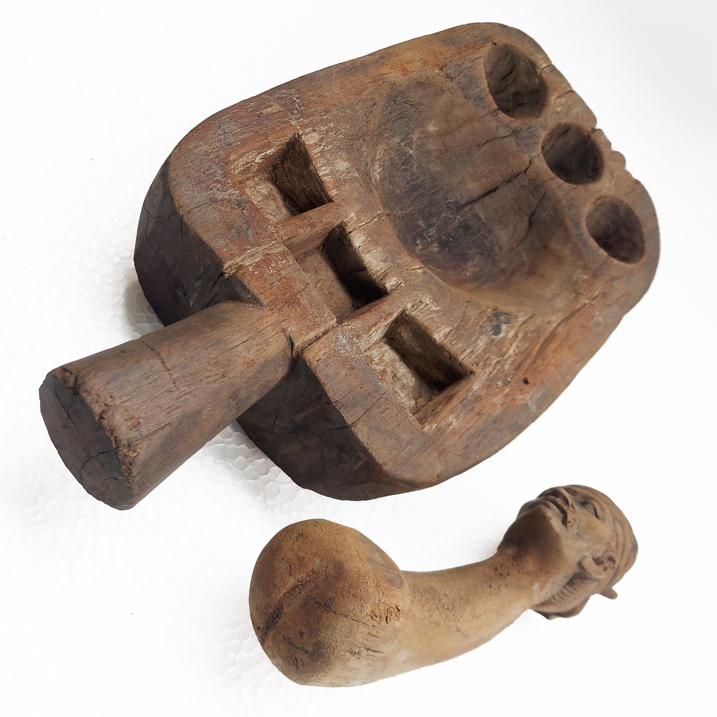 An old, hand-carved Asian wooden spice grinder set with signs of use on a white background.