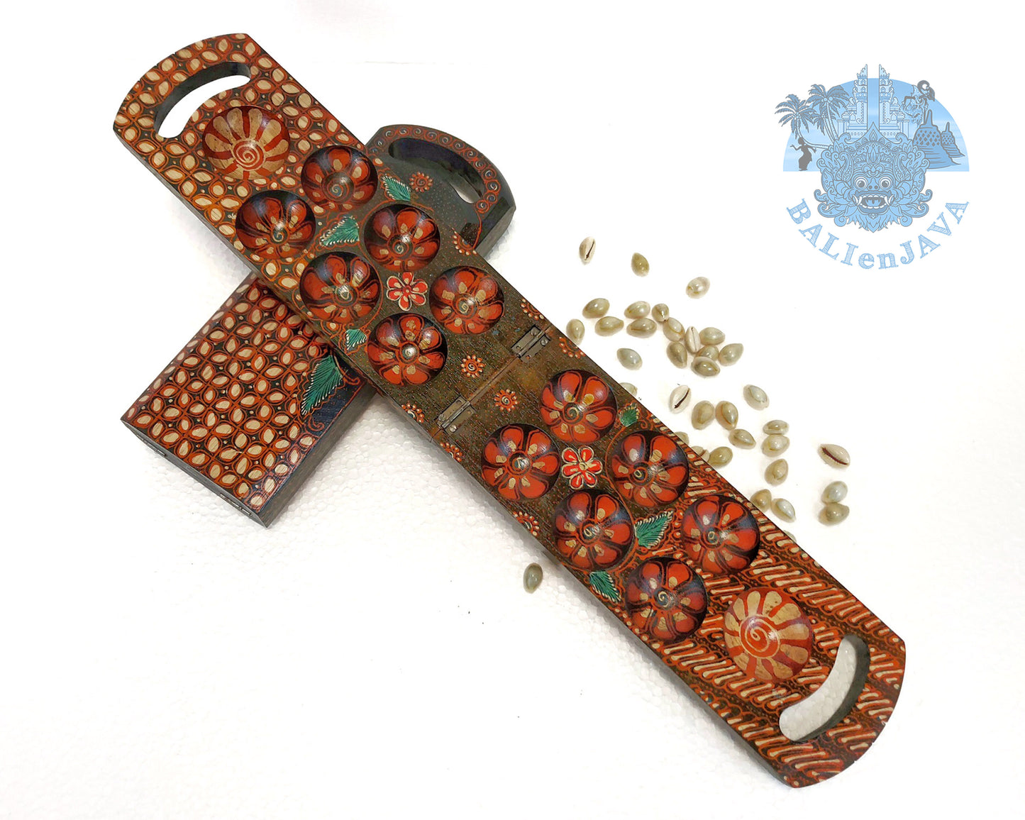 Wooden mancala boards with brown color batik patterns, along with cowrie shells on a white background.