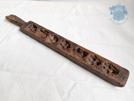 Old wooden cookie mold with decorative patterns and patina surface on a white background