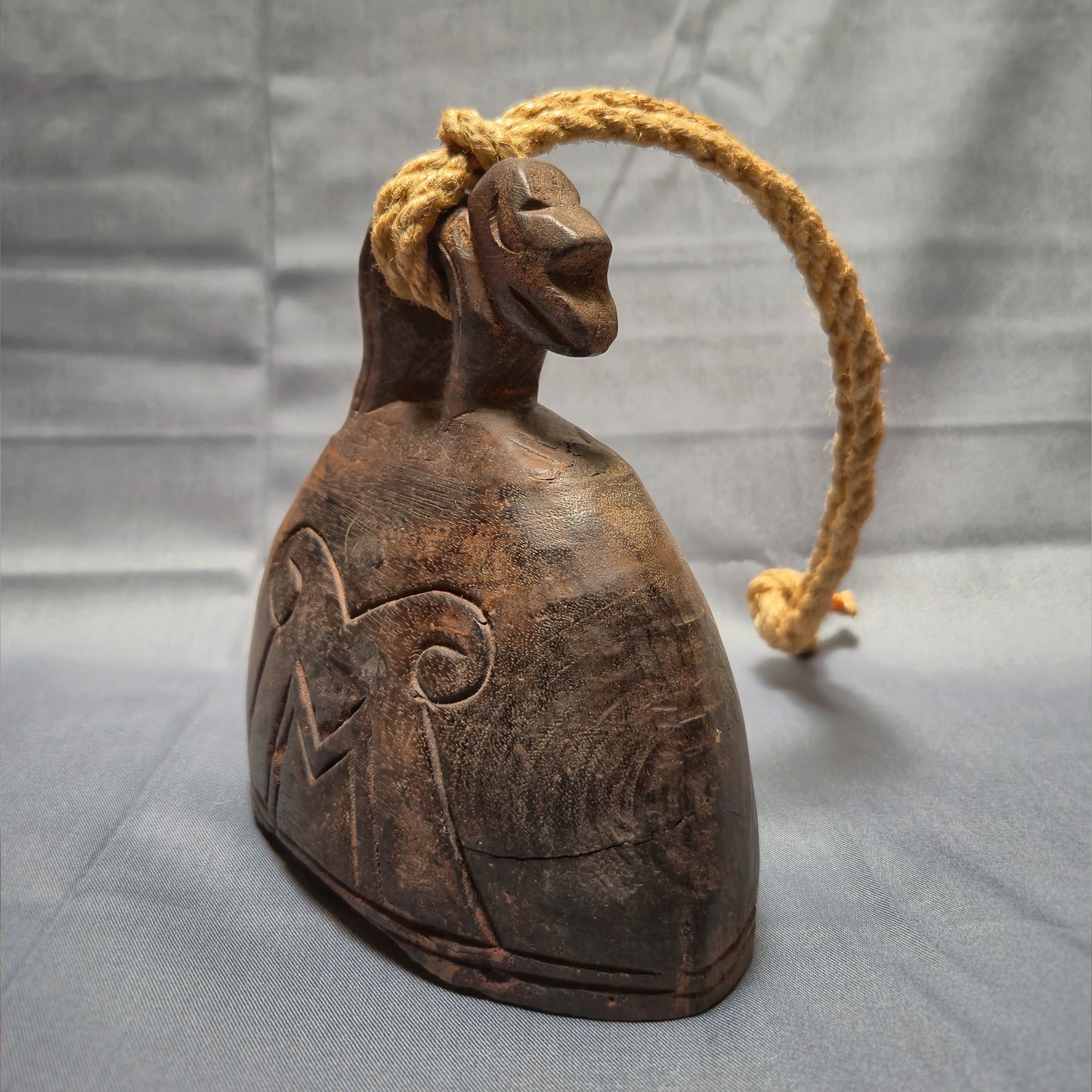 Wooden bell with rope on a gray background