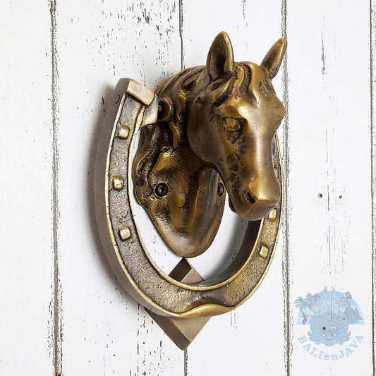 Brass horse head and horseshoe door knocker on a painted white wooden background