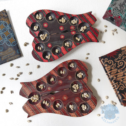 Decorative cat-shaped mancala with shells on a white surface.