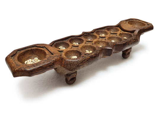 Coconut timber mancala board game with raised legs and cowrie shells on each playing holes, placed on white background.