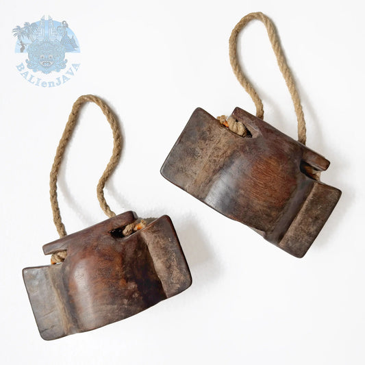 Two rustic wooden bells with natural fiber rope hangers, displayed on a clean white background.
