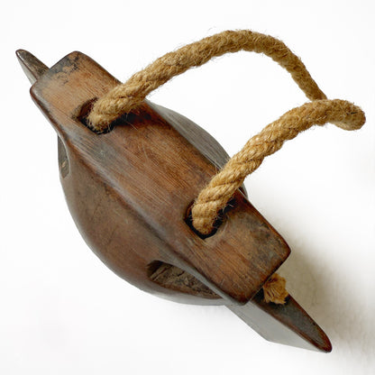 Top view of a wooden bell with a jute rope handle on a white background