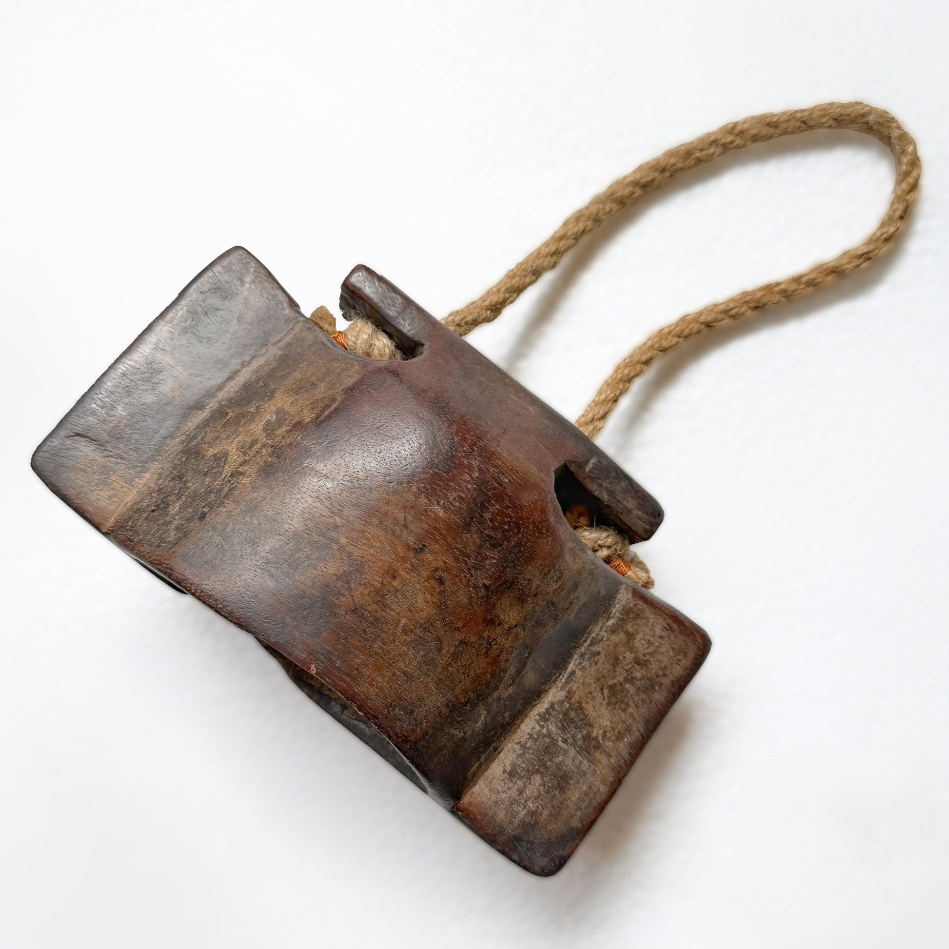 Vintage wooden cattle bell with a rope handle on a white background