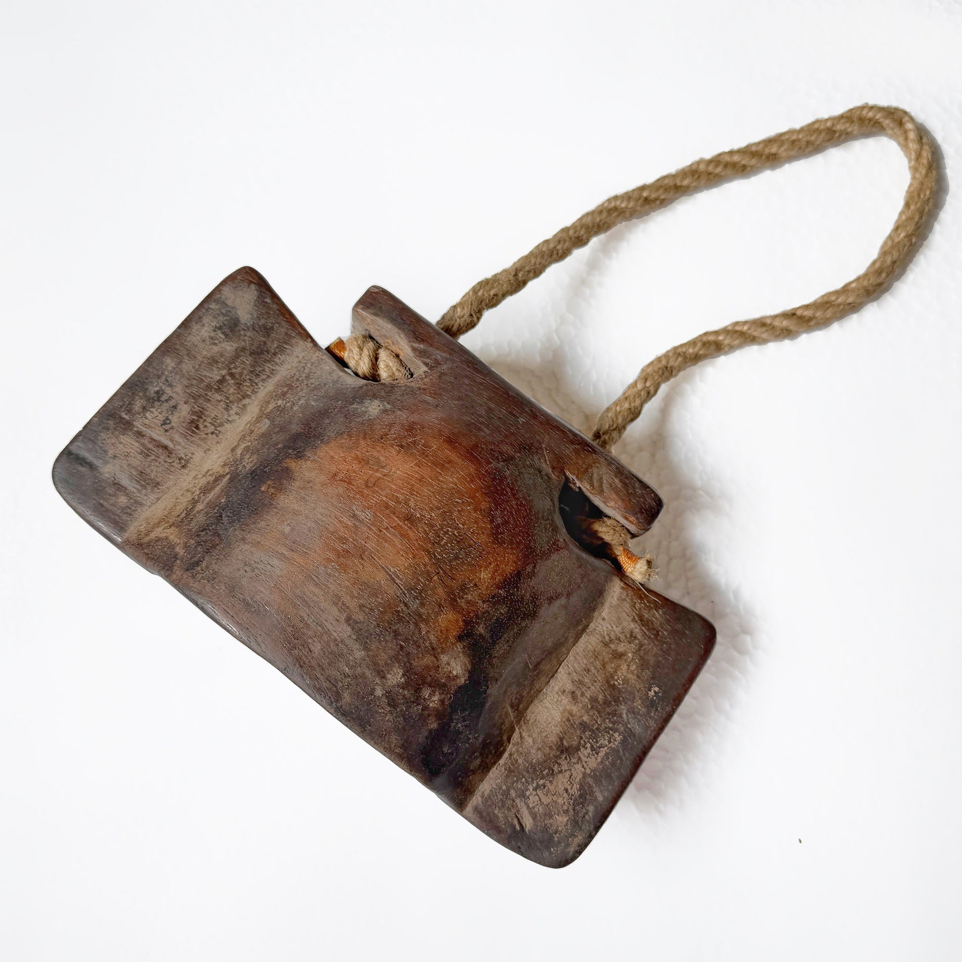 Wooden cowbell with a rope handle on a white background