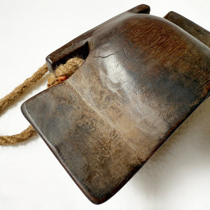 Vintage wooden bell with a rope handle on a white background