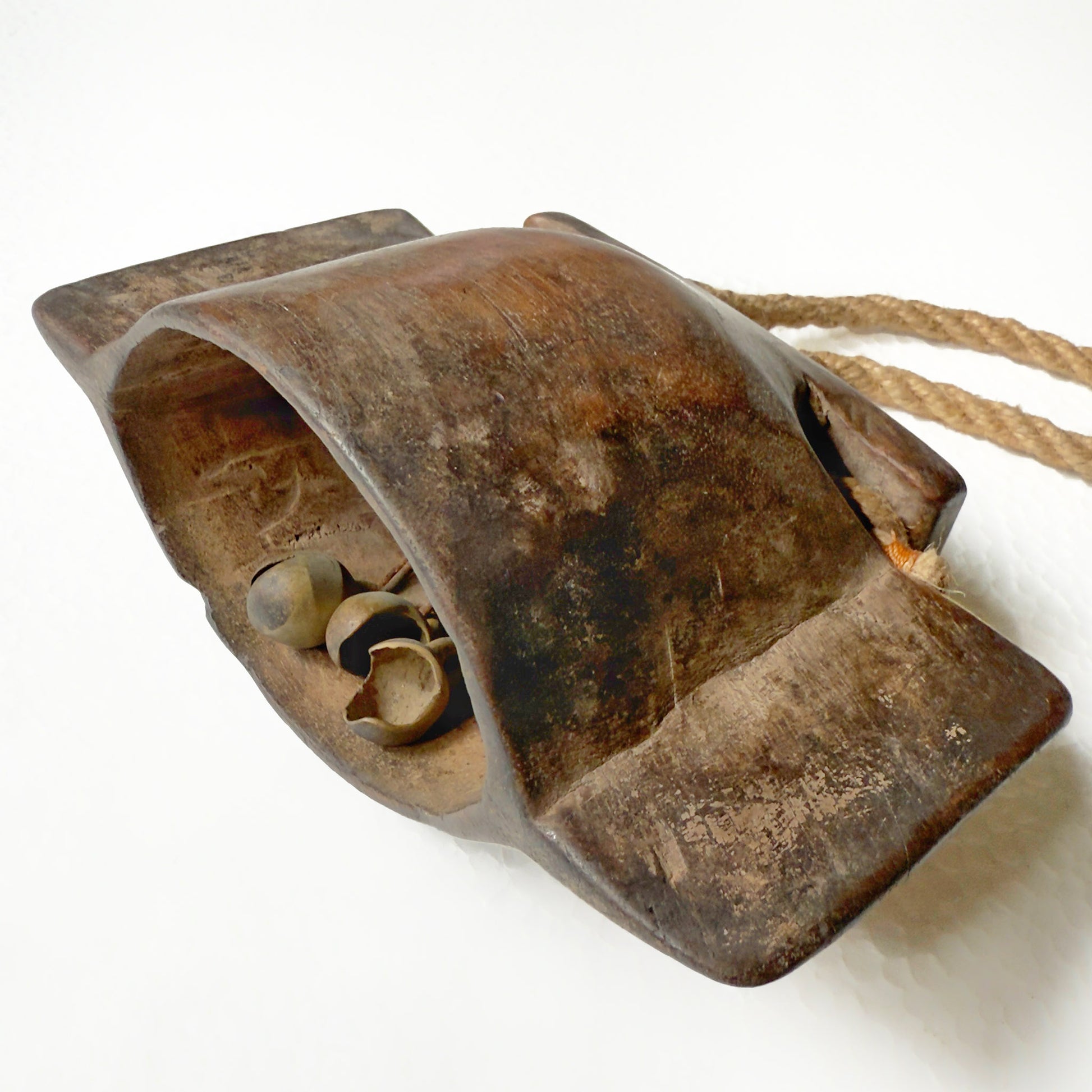Wooden bell with jute rope handle and weathered surface on a white background