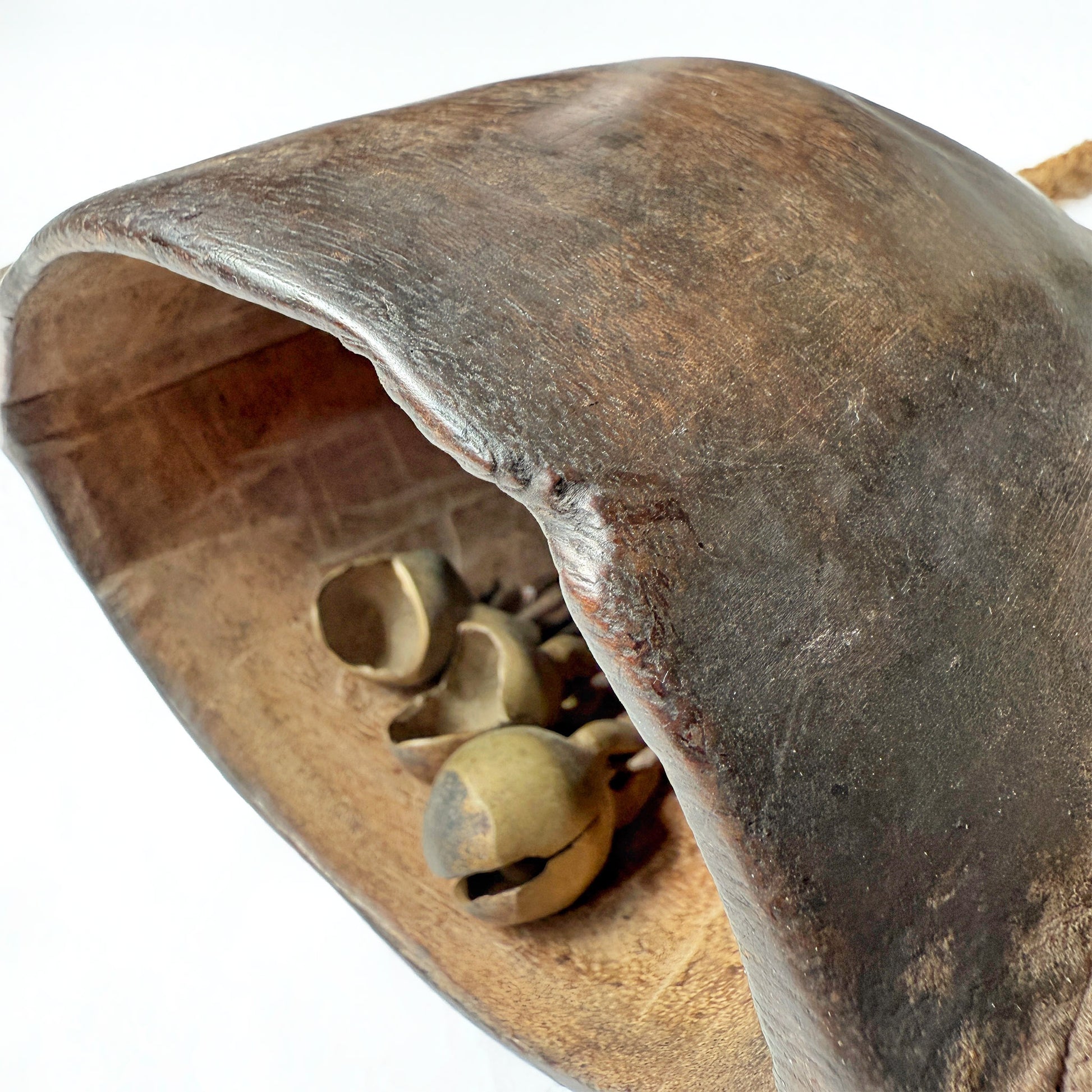 Close-up of a wooden bell with metal jingles on a white background