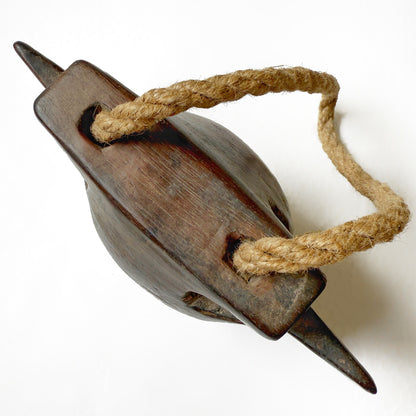 Top view of a wooden bell with a rope handle on a white background