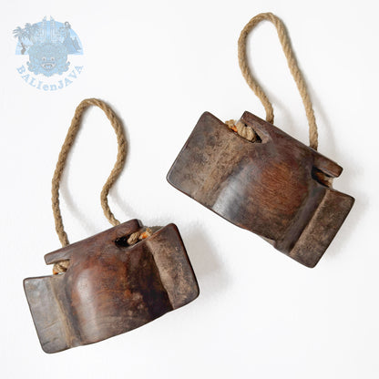 Two wooden bells with rope handle on a white background