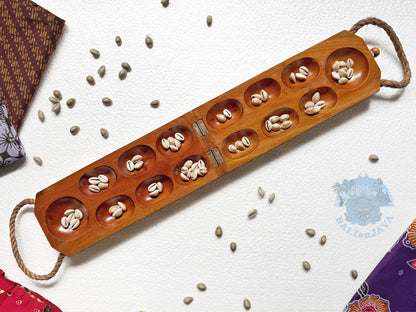 Wooden mancala board game with seeds on a white background