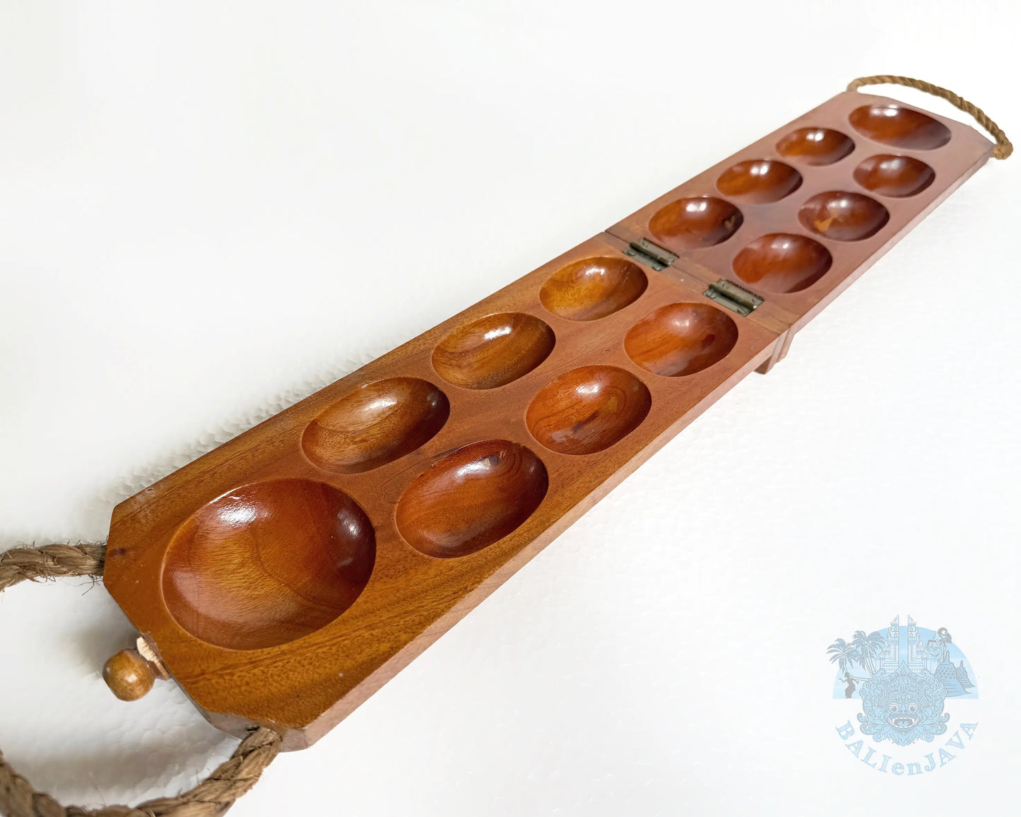 A rectangular wooden game board with multiple oval holes, shown on a plain white background. The board is medium brown wood with a visible grain, and rope handles attached at both ends.