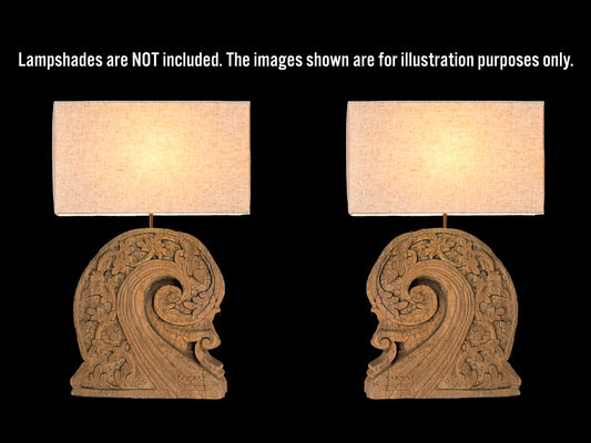 Two matching table lamps shown side by side on a black background, with white text at the top stating lampshades are not included and the images are for illustration purposes only. The lamps have carved ornate wood bases in a warm brown tone and rectangular cream lamp shades glowing with warm light.
