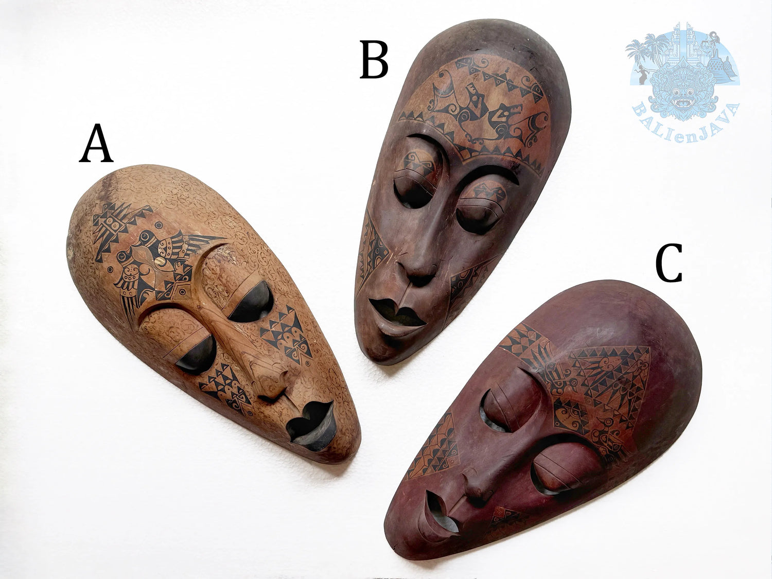 Three wooden masks with tribal patterns on a white background