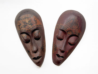 Two wooden masks with tribal patterns on a white background