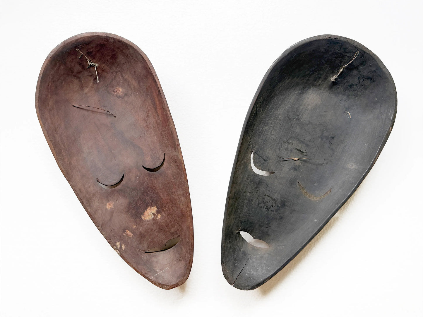 Two wooden masks back sides, one brown and one black, on a white background