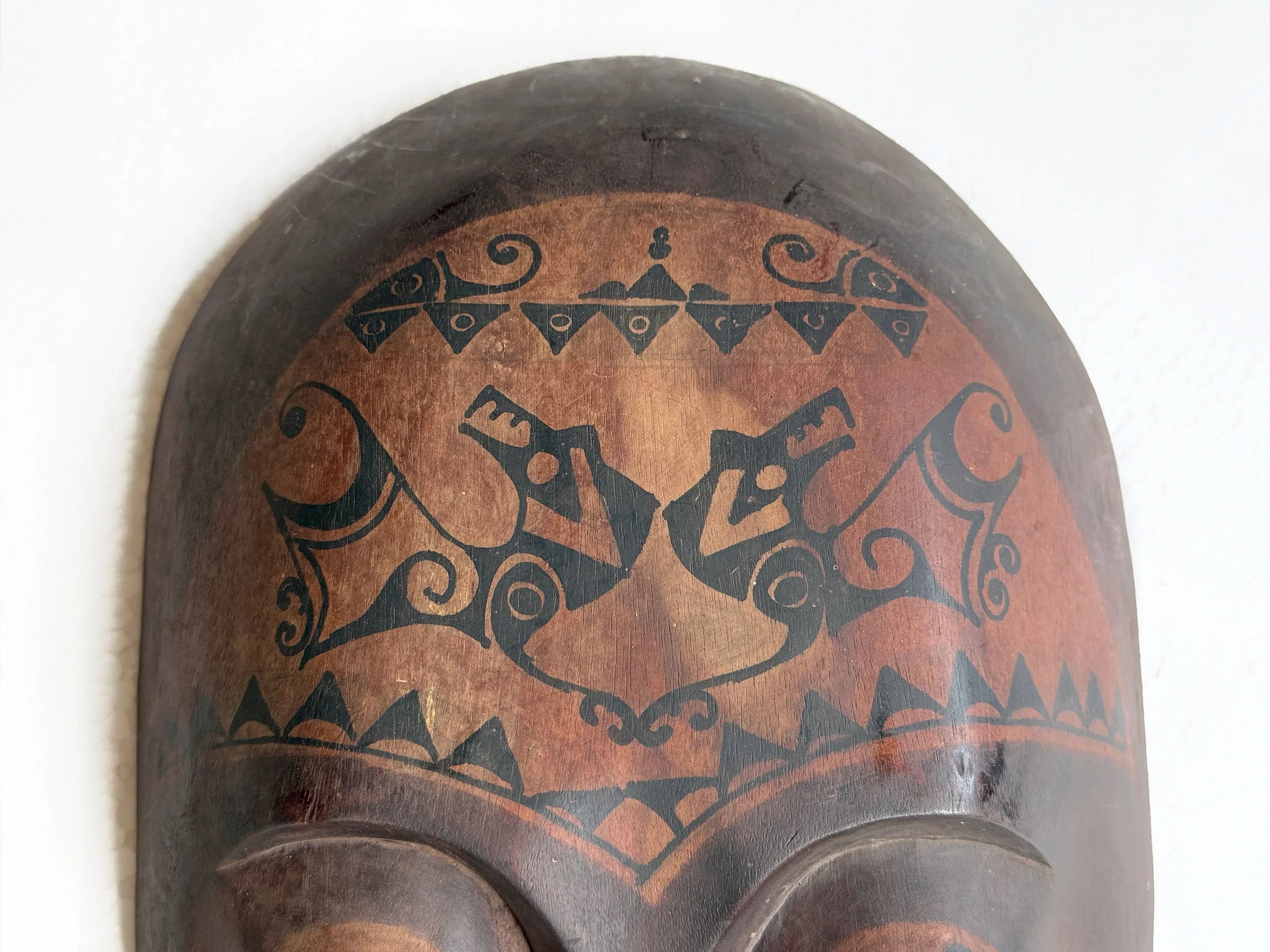 Decorative wooden mask with tribal patterns on a white background