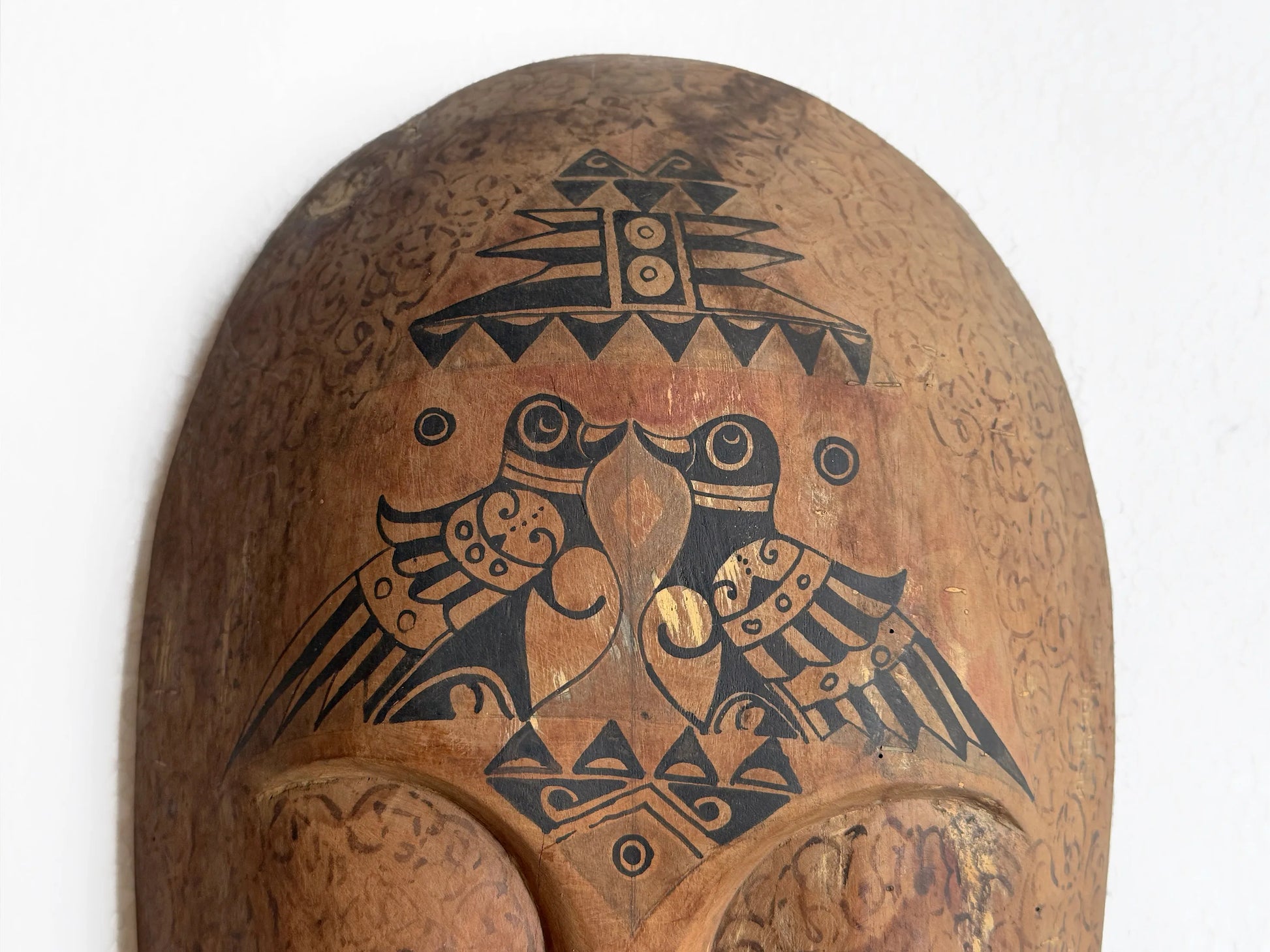 Wooden mask with black tribal patterns on a white background