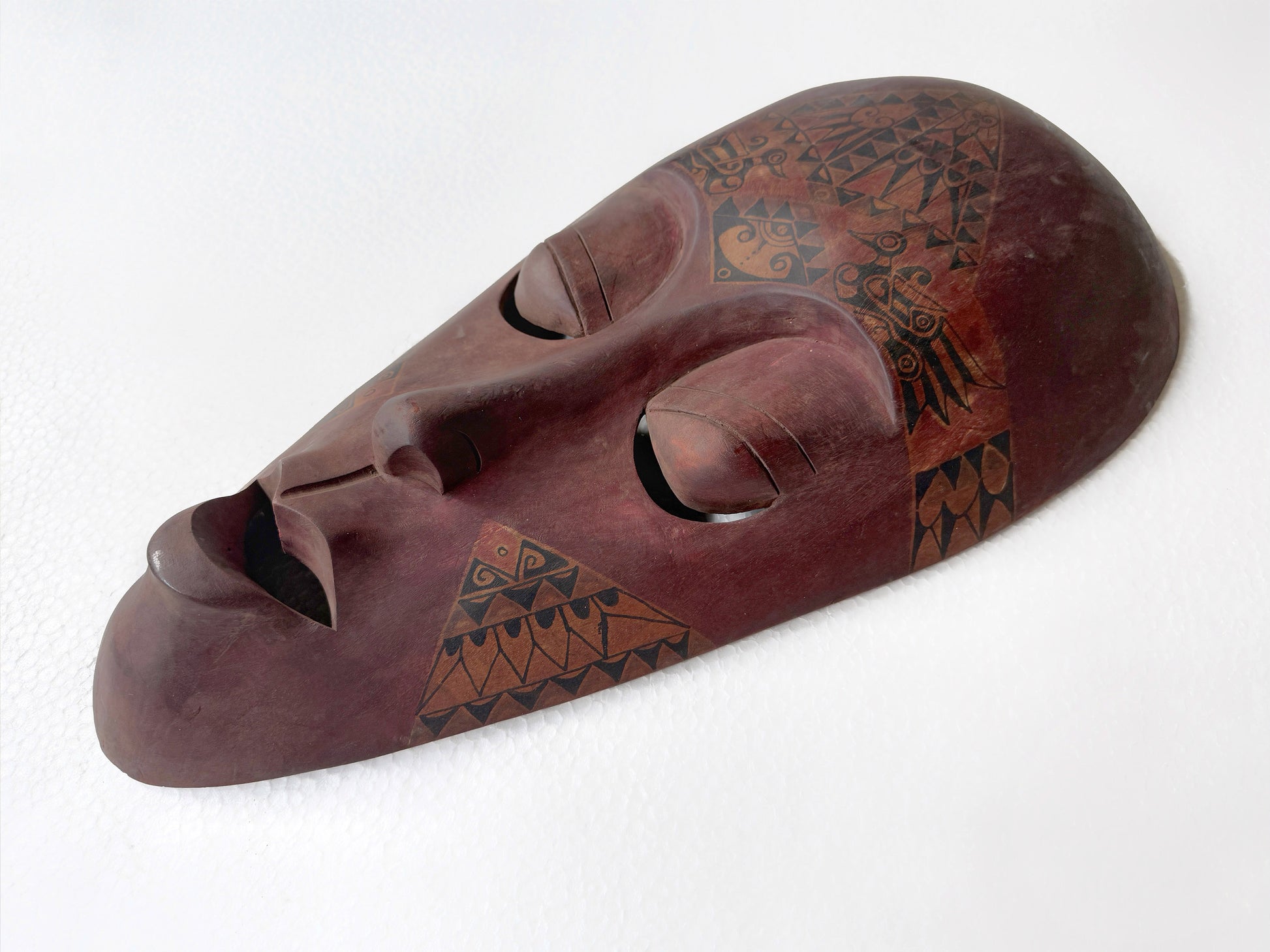 Wooden mask with tribal patterns on a white background