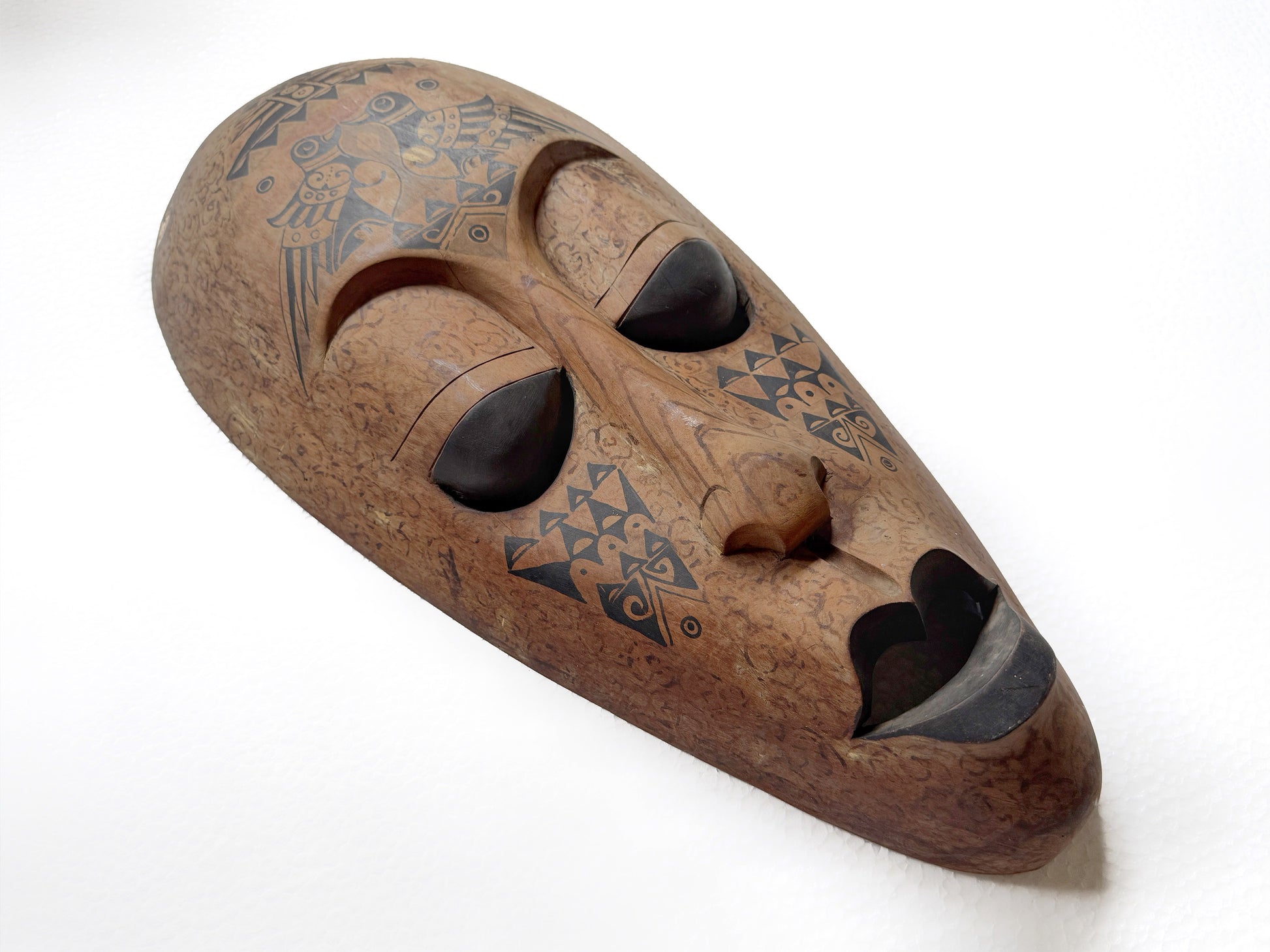 Wooden mask with geometric pattern on a white background