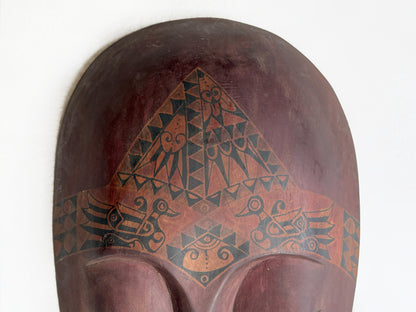 Decorative wooden mask with geometric patterns on a white background