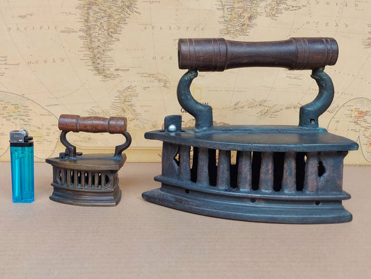 Two vintage clothes iron on a textured brown surface with a world map in the background