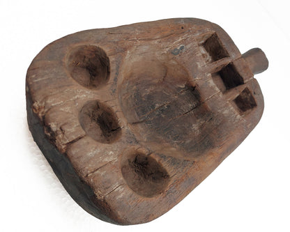 An old, hand-carved wooden pestle with signs of use on a white background.