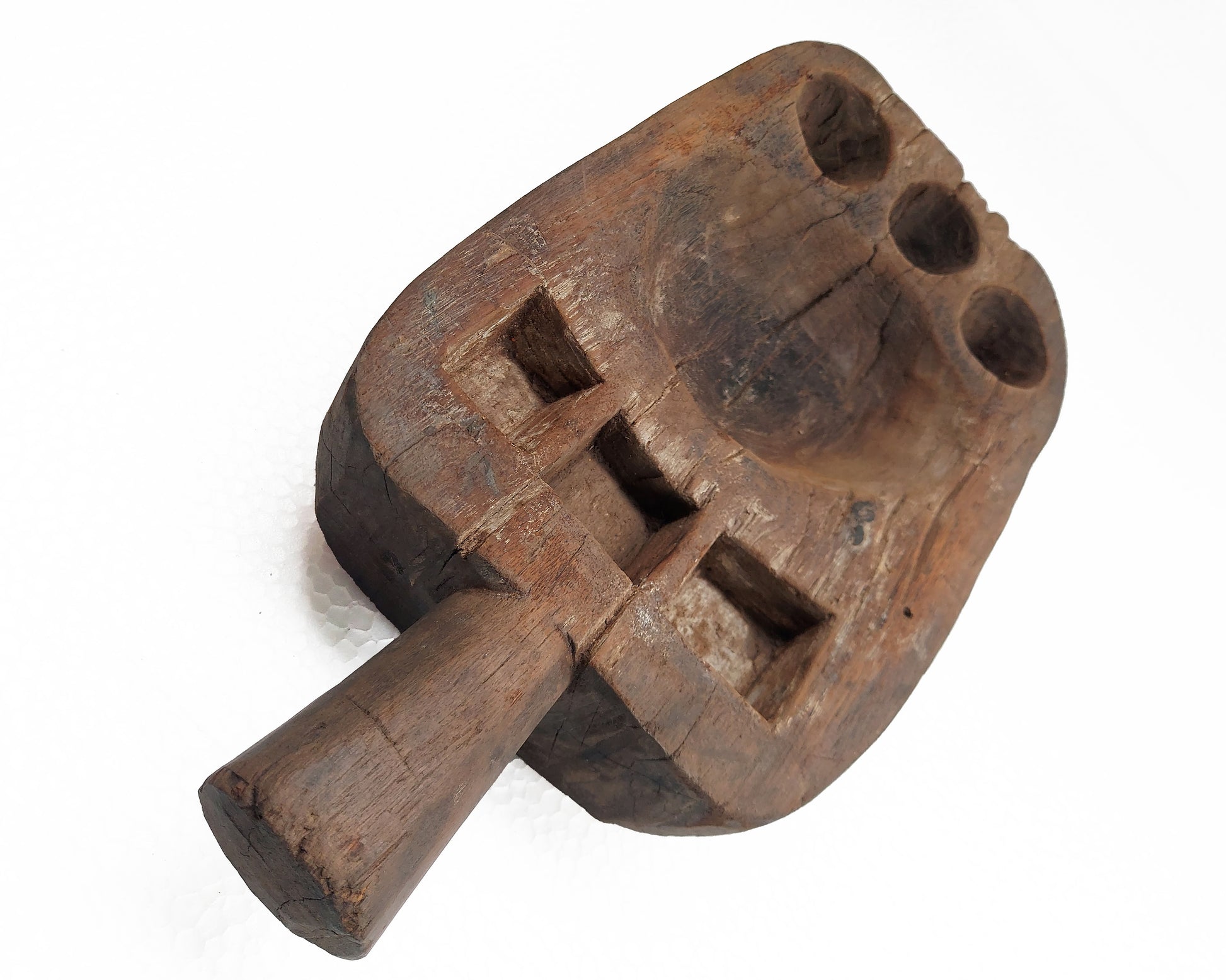 An old, hand-carved wooden pestle with signs of use on a white background.
