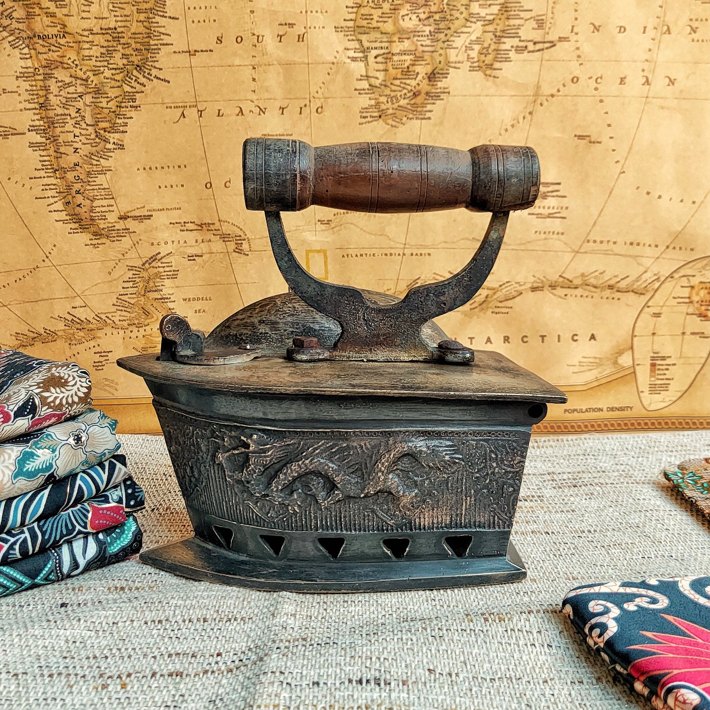Vintage-style iron with decorative elements on a textured surface with a world map in the background