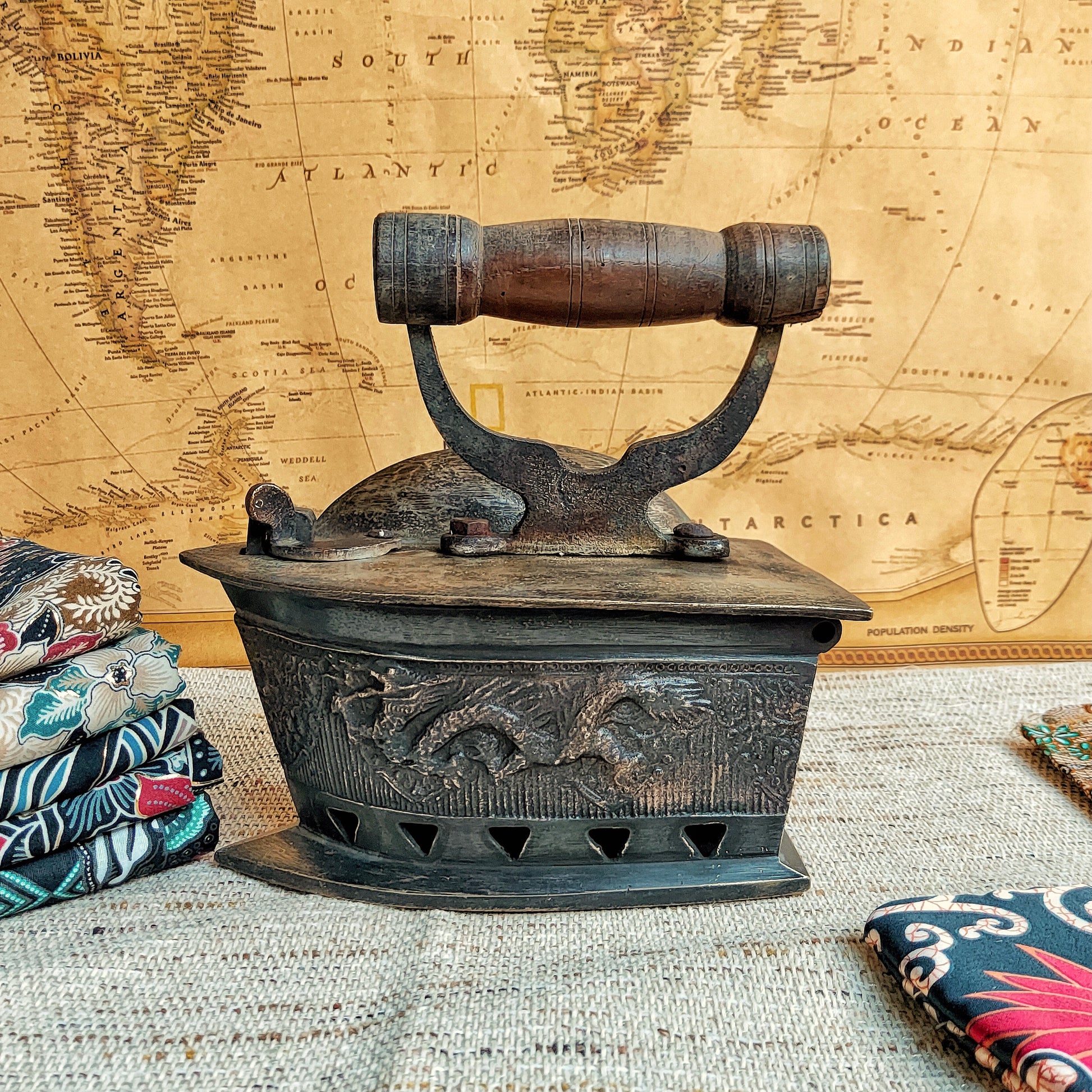 Vintage-style iron with decorative elements on a textured surface with a world map in the background