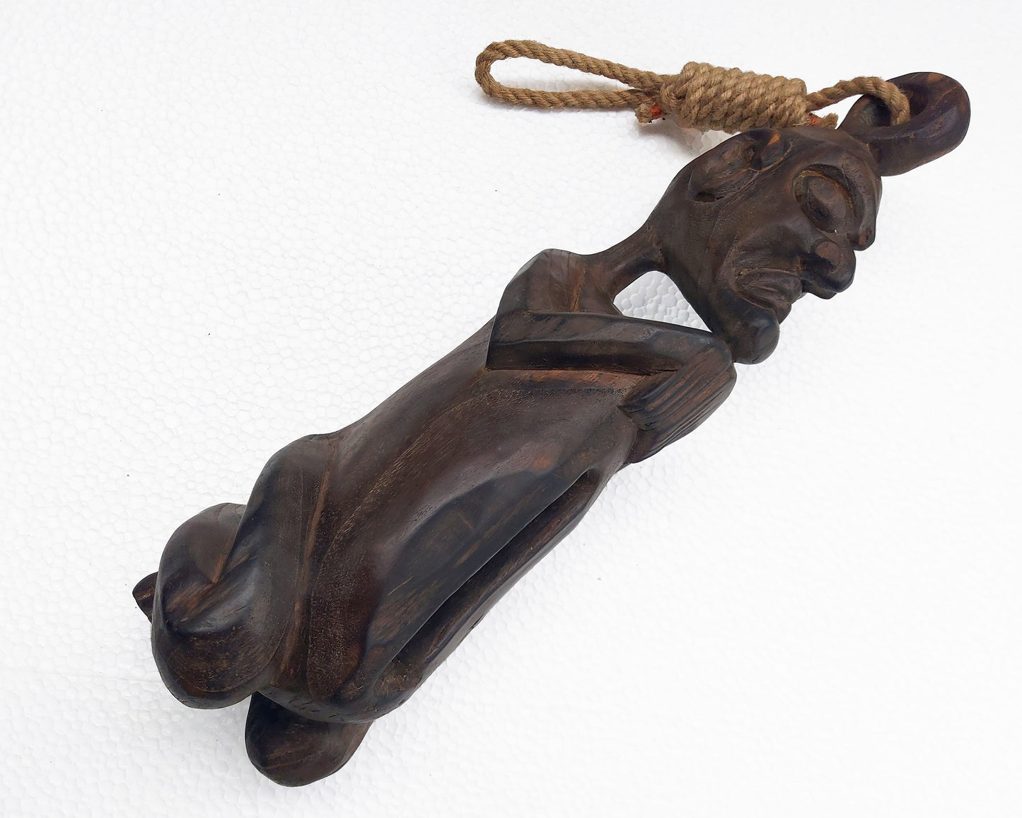 A vintage wooden slit drum from Papua, carved in the shape of a reclining figure, with a rope attached to its top.