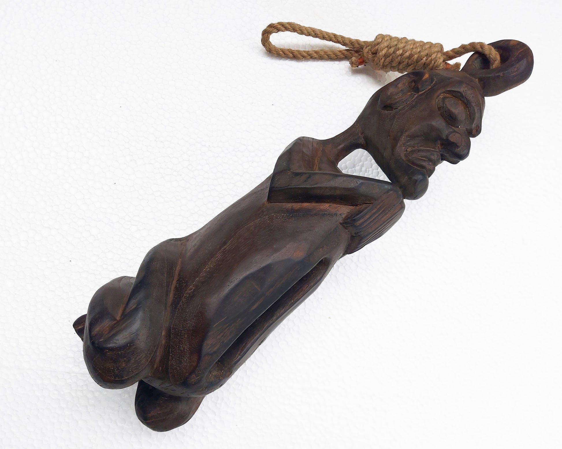 A vintage wooden slit drum from Papua, carved in the shape of a reclining figure, with a rope attached to its top.