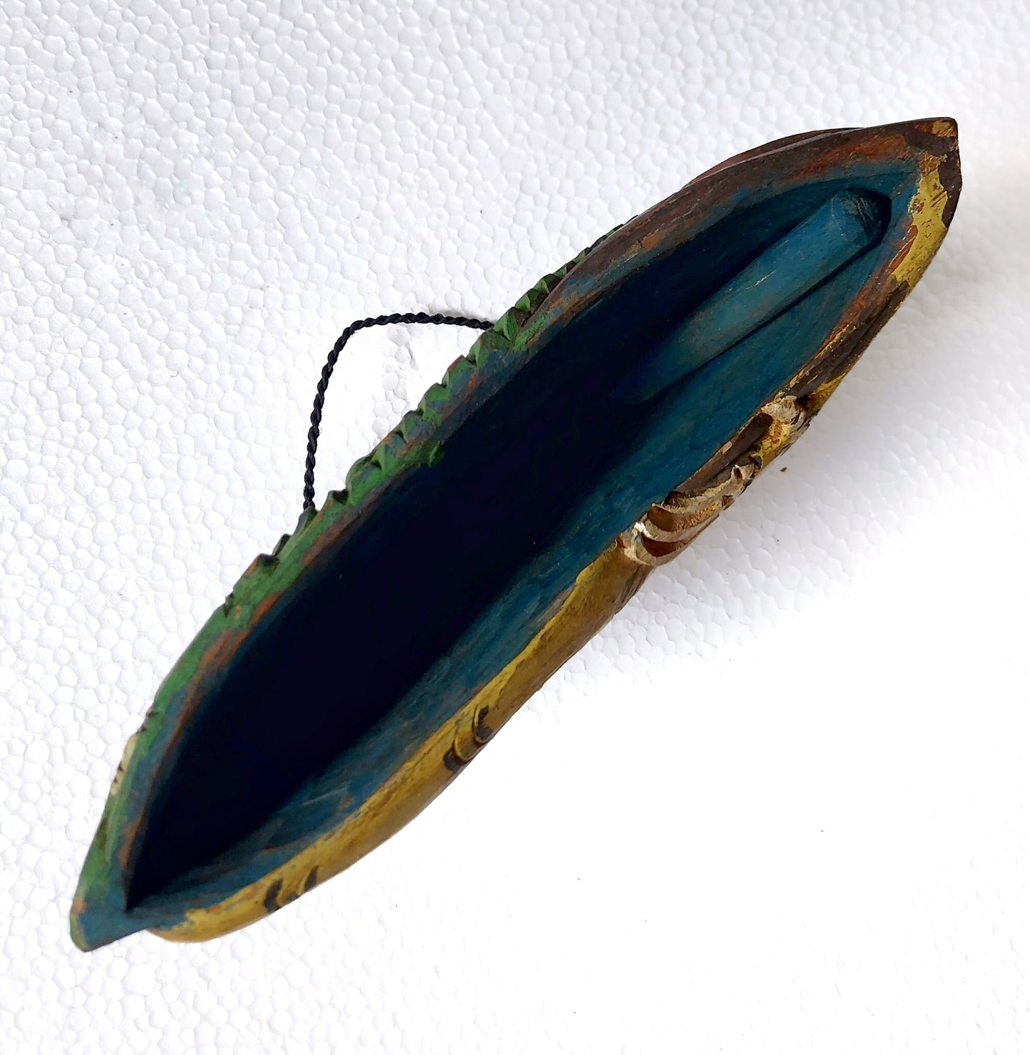 Bottom part of a wooden bell with the wooden clapper visible 