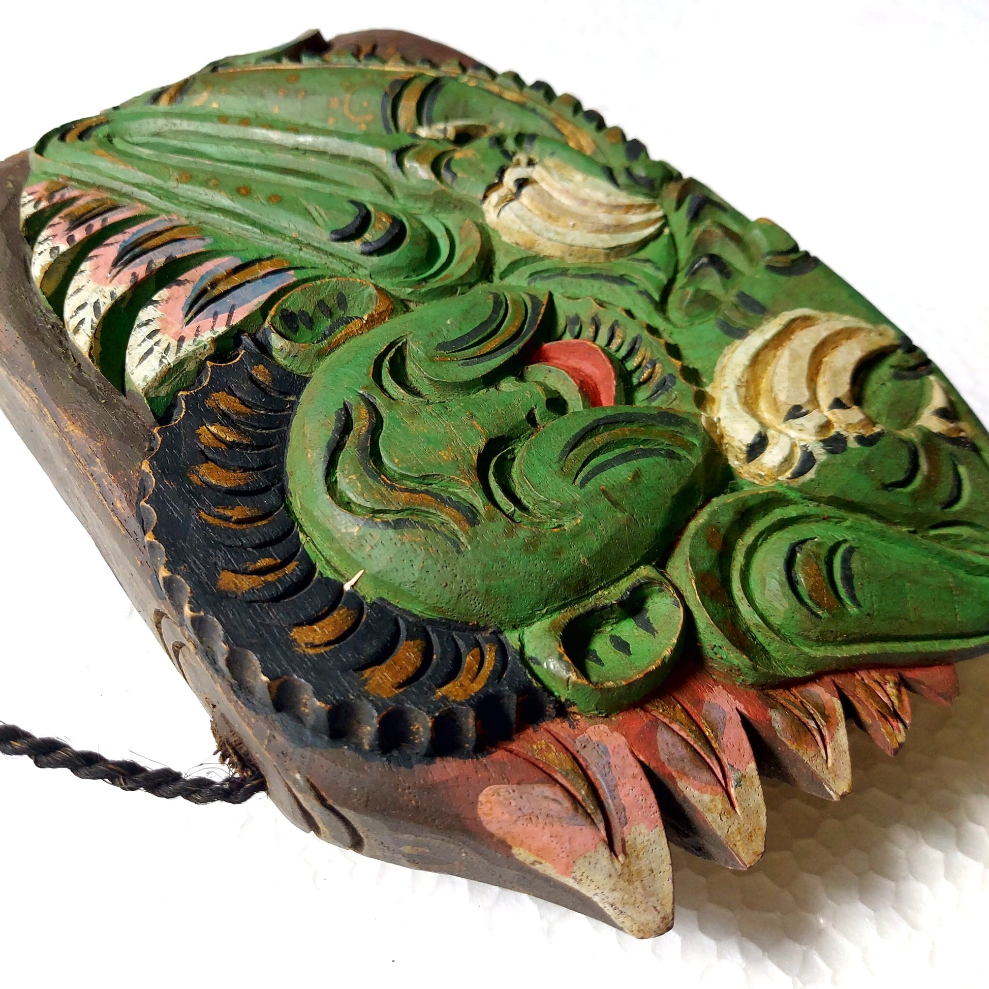 Close-up of a wooden bell with carving of a green mythological creature 