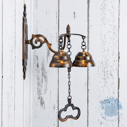 Decorative wall-mounted bell with chains on a painted white wooden background