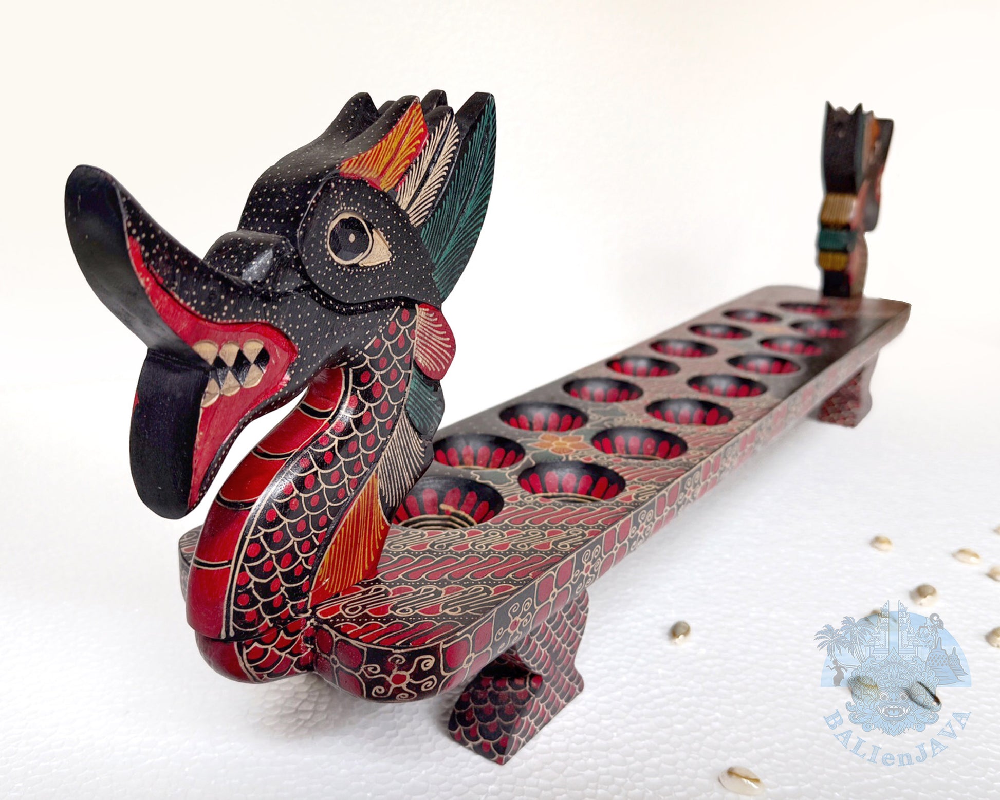 Mancala board game resembling a dragon with a long, narrow body and two heads with painted scales pattern.