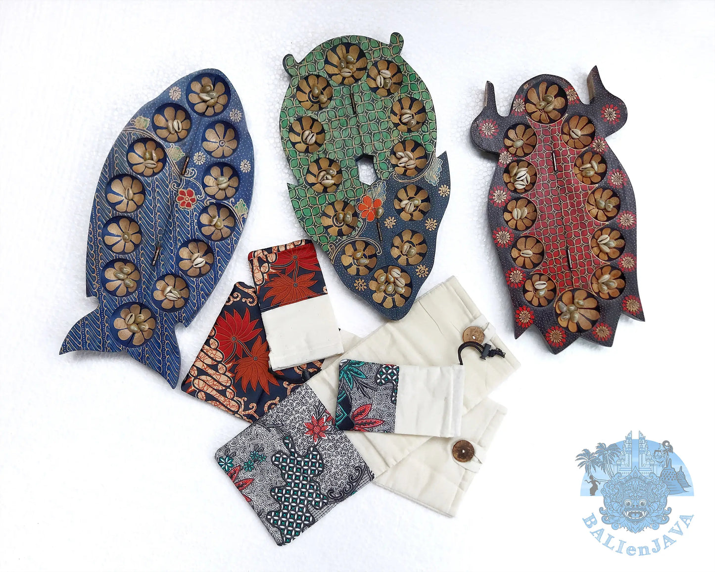 Three decorative wooden mancala game shaped like a fish, owl, and duck, displayed alongside several small fabric pouches on a white background. 