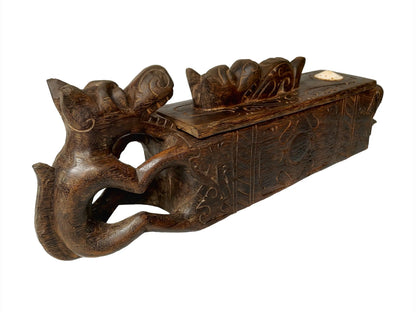 A dark brown carved wooden box with a lid, featuring a sculpted handle shaped like a stylized dragon figure, shown against a plain white background.