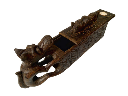 A dark brown carved wooden box with dragon-like figure, featuring a sliding lid and a small handle on top, shown against a plain white background.