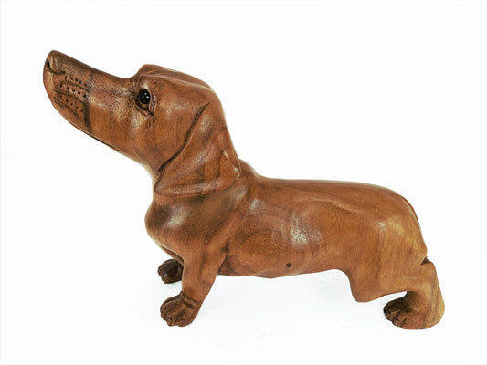 A carved wooden dachshund figurine with a glossy finish, shown in profile against a plain white background.