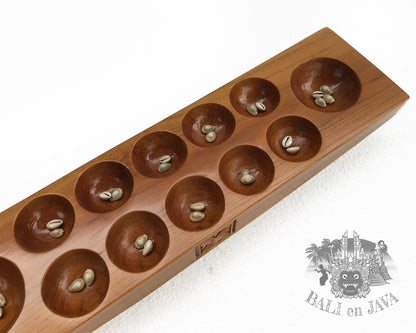 Wooden mancala board game with seeds on a white background