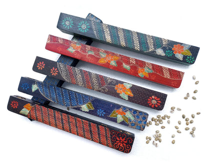 Five mancala board games with hand-painted design arranged on a white background with cowrie shells scattered around