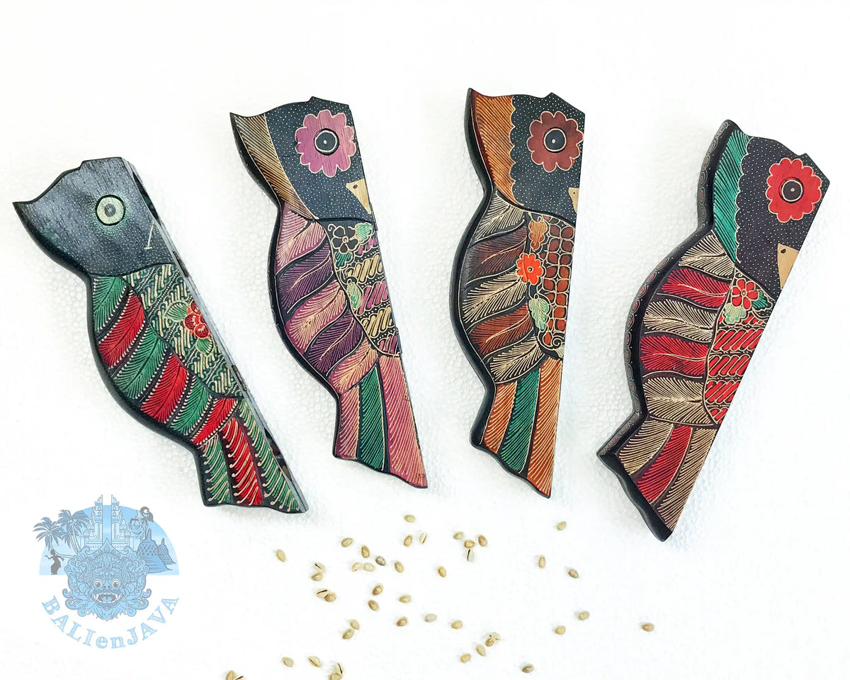 Three owl-shaped wooden mancala board games shown in folded position, with various colorful patterns, and some cowrie shells scattered on a white background.
