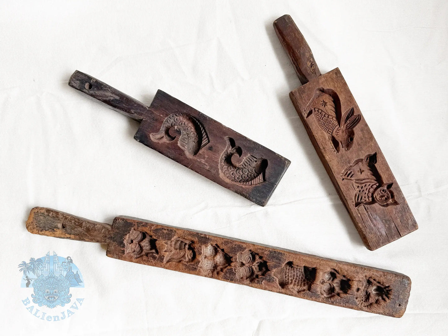 Three wooden cookie molds with engraved designs on a white background