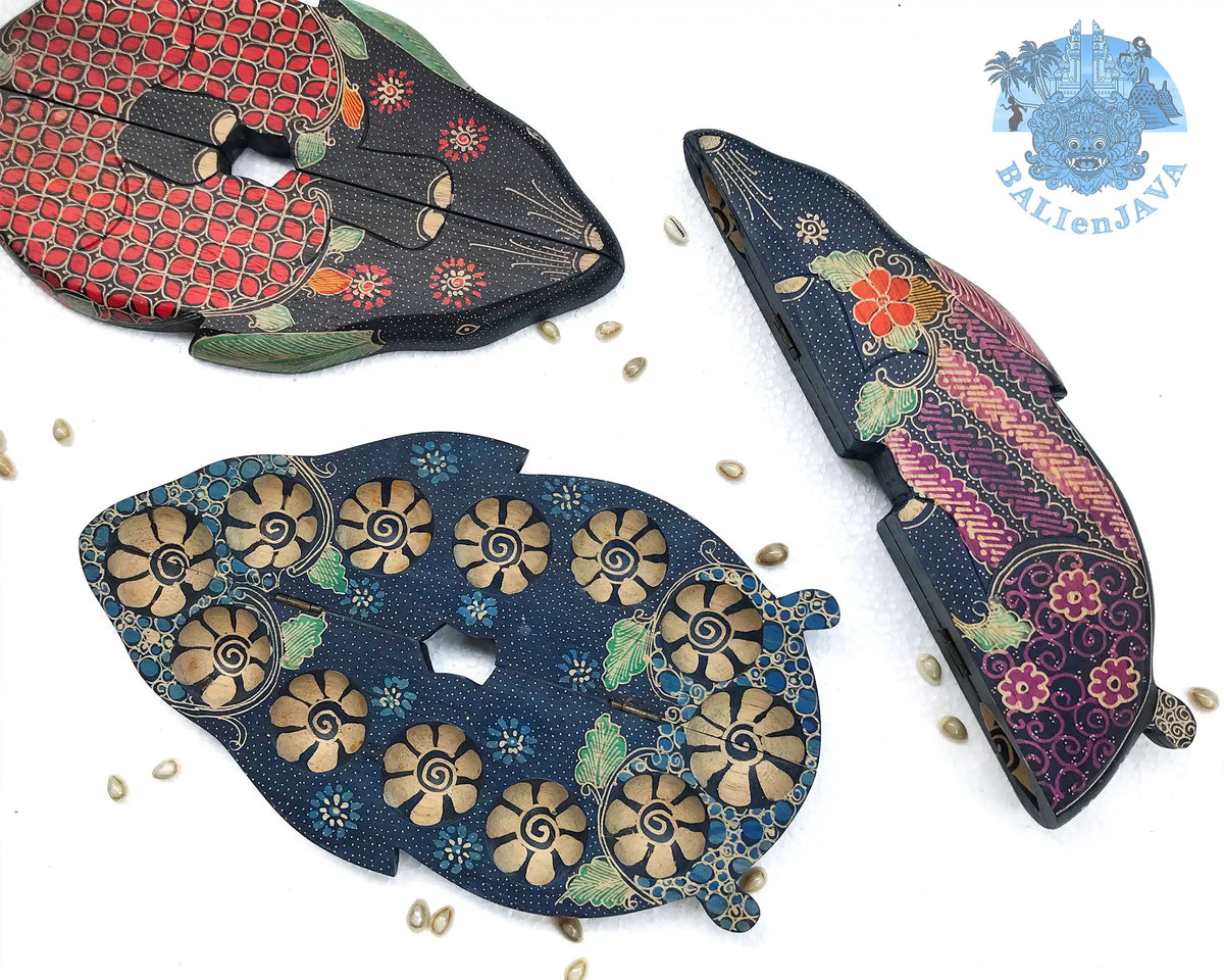 Three wooden rabbit-shaped board games with circular pits and intricate patterns, displayed on a white background with scattered cowrie shells.