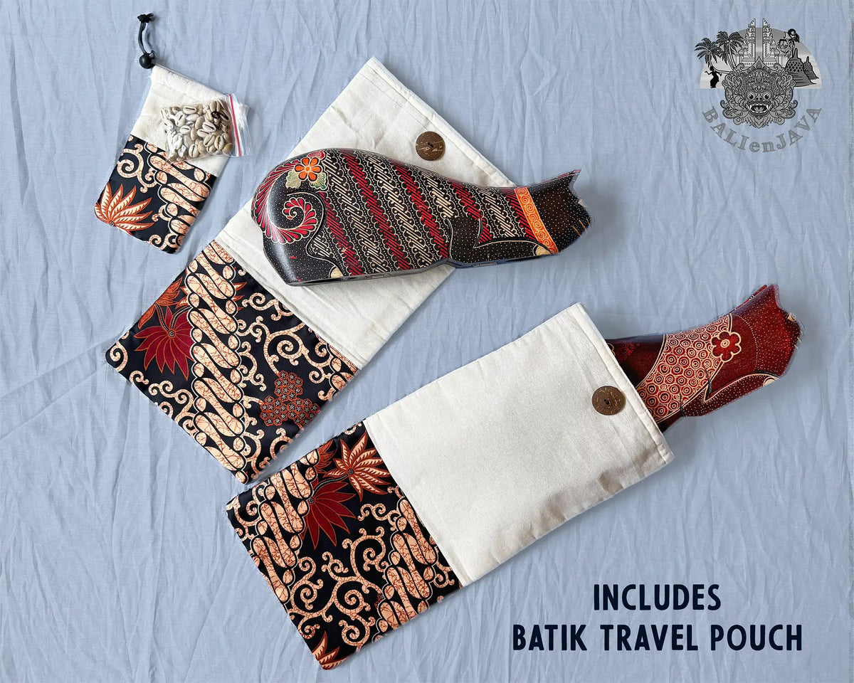 A travel pouch set laid flat on a light blue fabric background, including a larger pouch with a red and black batik patterned end, a matching smaller pouch, and two cat-shaped board games. Text reads 'INCLUDES BATIK TRAVEL POUCH' and a logo appears in the top right.