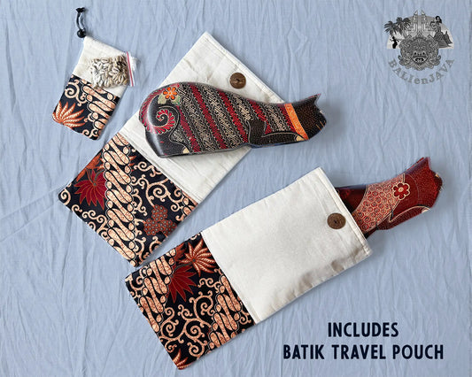 A travel pouch set laid flat on a light blue fabric background, including a larger pouch with a red and black batik patterned end, a matching smaller pouch, and two cat-shaped board games. Text reads 'INCLUDES BATIK TRAVEL POUCH' and a logo appears in the top right.